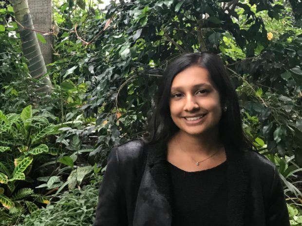 Mili standing in front of a bush, facing the camera and smiling