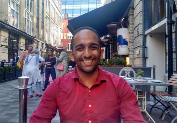 Vishal sitting outside a cafe, facing the camera and smiling