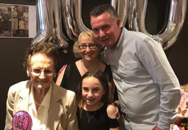 Two adults and a child with someone celebrating their 100th birthday.