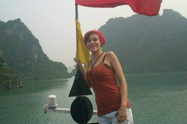 blog post author standing on a boat, facing the camera, a lake and mountains in the background