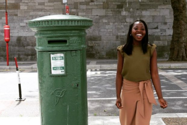 Racheal smiling and standing next to a post box.