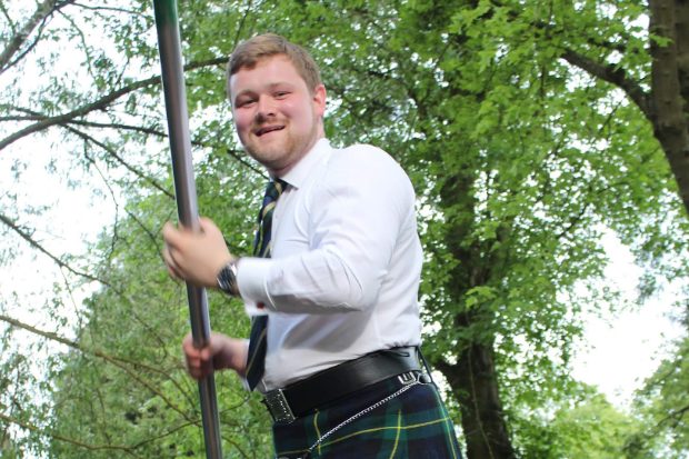 Sean standing in front of a tree and holding a boat paddle.