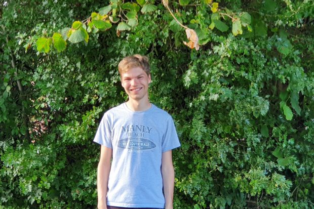 Scott smiling and standing in front of a bush.