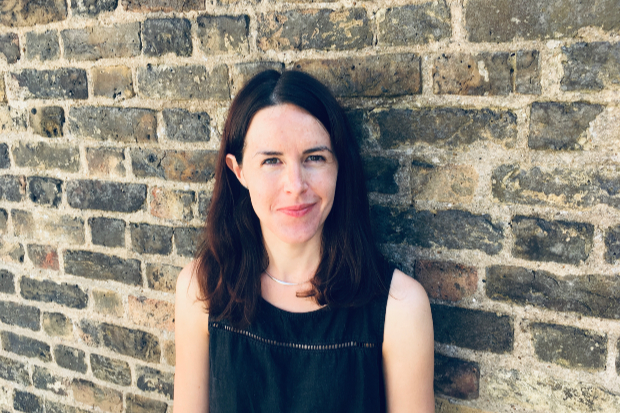 Helen standing against a wall, smiling at the camera.